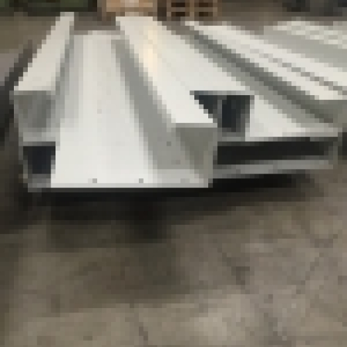Bunke af CNC-kantpressede metaldele stablet i en produktionshal, klar til videre montage.