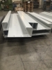 Bunke af CNC-kantpressede metaldele stablet i en produktionshal, klar til videre montage.